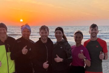 Gruppe Läufer steht vor dem Meer beim Sonnenaufgang